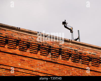 Sorveglianza / videocamera di sicurezza sulla parte superiore di un edificio in mattoni Foto Stock