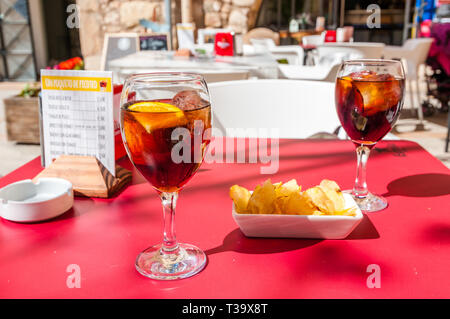 Due bicchieri con nero vermouth, ghiaccio e arancio, trucioli, bar terrazza Foto Stock