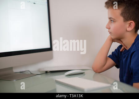 Preoccupato cerca ragazzo adolescente utilizzando un pc a casa Foto Stock