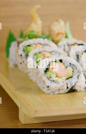 Maki roll con gamberi fritti, avocado e lattuce sul piatto di legno Foto Stock