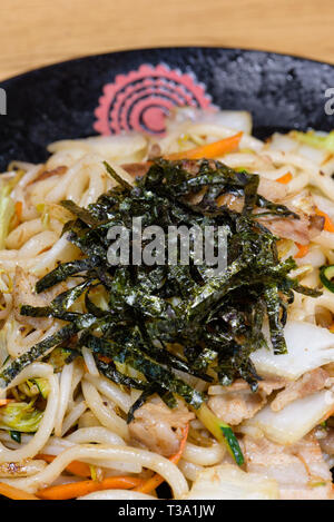 Tagliatelle con verdure grigliate e alghe fritte e grigliate di carne di maiale, le carote e i germogli di soia in una circolare per piastra nera Foto Stock