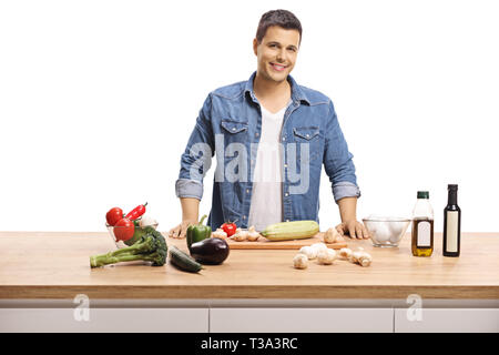 Sorridente giovane ragazzo cucinare con ingredienti sani in un contatore di legno isolato su sfondo bianco Foto Stock