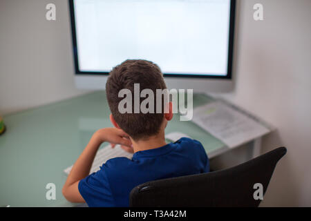 Poco dipendente gamer kid riproduzione su PC in ambienti interni Foto Stock