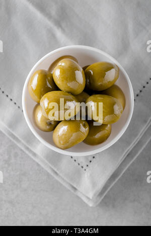 Tipiche italiane olive verdi in una ciotola sul tavolo di calcestruzzo. Concetto di antipasti dalla cucina italiana. Vista da sopra con copia spazio. Foto Stock