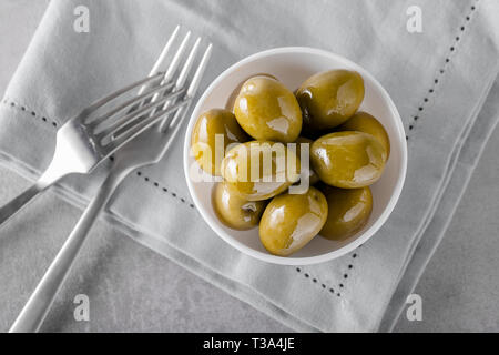 Tipiche italiane olive verdi in una ciotola sul tavolo di calcestruzzo. Concetto di antipasti dalla cucina italiana. Vista da sopra con copia spazio. Foto Stock