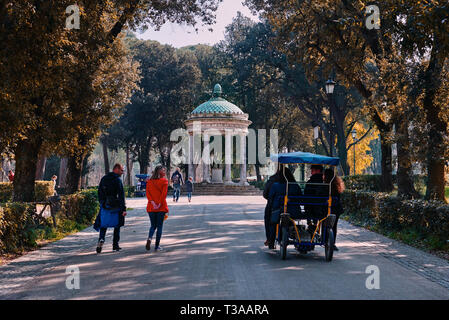 Roma, Italia, 19 febbraio 2019, Villa Borghese, una coppia entra a sinistra di un'auto elettrica, padre e figlio in background nei pressi del Tempio di Diana Foto Stock