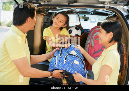 Felice famiglia vietnamita di mettere nello zaino nel baule auto prima di partire per le vacanze Foto Stock