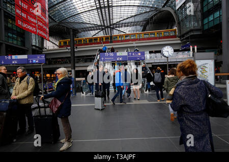 Pendolari, viaggiatori, turisti all'interno del centro commerciale Berlin Hauptbahnhof con un treno S-Bahn che passa attraverso l'aereo, Berlino, Germania Foto Stock