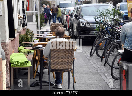 Karlsruhe, Germania. 02Apr, 2019. Nel sud Waldstrasse, un uomo si siede sul marciapiede in area esterna e di un ristorante. A destra è possibile vedere le auto in sosta su di una corsia di parcheggio. Sarà stretto in Germania il marciapiedi. Ora coloro che appartengono vi lotta indietro: pedoni. (A dpa " lotta per il marciapiede: pedoni difendersi contro ostacolo corso') Credito: Uli Deck/dpa/Alamy Live News Foto Stock