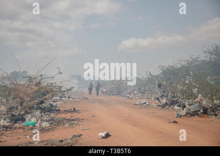 Dadaab, Kenya. 9 Ott, 2018. Poliziotti keniota veduto camminare in mezzo a bruciare i rifiuti in un campo di rifugiati. Dadaab è uno dei più grandi campi profughi nel mondo. Più di 200.000 rifugiati vivono lì - per la maggior parte dei somali fuggiti dalla guerra civile o la fame in Somalia. Credito: Sally Hayden SOPA/images/ZUMA filo/Alamy Live News Foto Stock