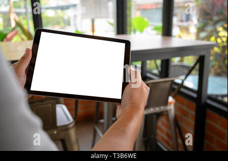 Imprenditore lavora a mano su tablet sulla scrivania in legno tablet con schermo vuoto mockup digitali computer tablet Foto Stock