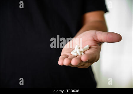 Man mano che tiene la medicina frug bottiglia sul supplemento a base di erbe pillola mangiare sano Foto Stock