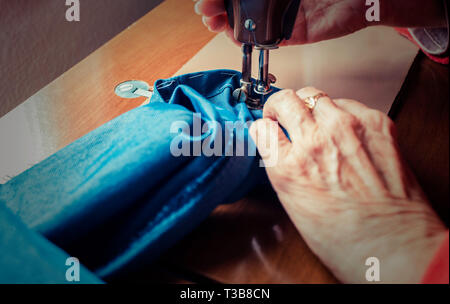 Processo di cucitura dei jeans donna vecchia le mani dietro la cucitura. jeans workshop Foto Stock