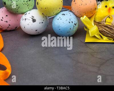 Un simpatico pulcino di Pasqua in un nido circondato da uova colorate, cartolina di pasqua Foto Stock