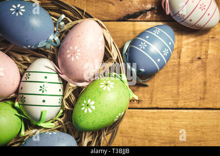 Colorate le uova di Pasqua su sfondo di legno, vista dall'alto con copia spazio. Vintage foto dai toni. Foto Stock