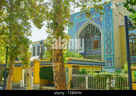 La vista sulla piastrella portale di Malek museo con modelli di ornati e scolpiti muqarnas passaruota attraverso il lussureggiante giardino di Bagh-e Melli trimestre, Teheran, Ira Foto Stock