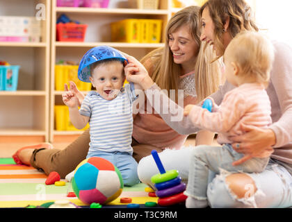 Le madri con bambini a giocare nella sala giochi. I bambini si divertono in vivaio Foto Stock