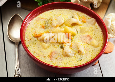 Minestra di verdura con ingredienti carote, cavolfiore, patate e prezzemolo nel recipiente rosso Foto Stock