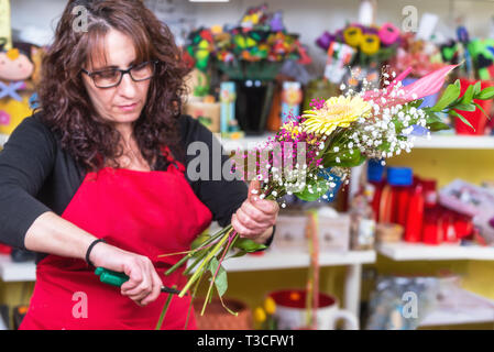 Ritratto di donna fioraio indossando il grembiule in piedi al bancone rendendo bouquet per cliente al negozio di fiori . Foto Stock