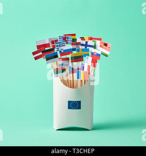 Set di diverse bandiere di carta in una scatola di cartone decorata con segno dell'UE su sfondo verde con copia spazio. Economico, politico Unione di Stati europei Foto Stock