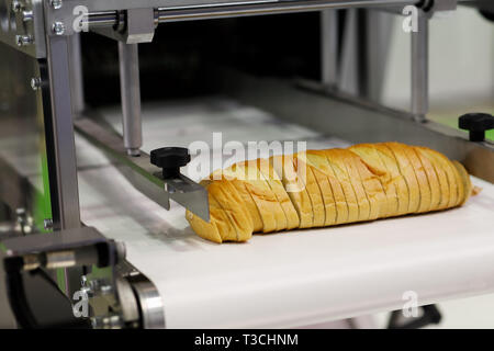 Industriali pane automatico macchina affettatrice per panetterie. Messa a fuoco selettiva. Foto Stock