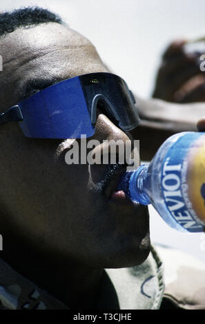 Il 30 ottobre 1993 un nero DEGLI STATI UNITI Soldato dell'esercito della 24a divisione di fanteria, assume una bevanda di acqua avendo appena arrivati in nave a Mogadiscio è di nuovo porto, Somalia. Foto Stock