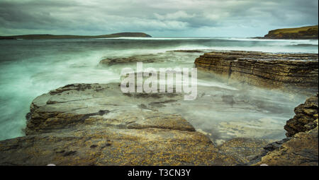 Una lunga esposizione immagine del mare la rottura sulle formazioni rocciose a metà Howe, Rousay, Orkney Islands Foto Stock