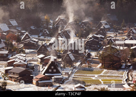Morning sun hits the first snow of the year  Ogimachi Village.  Water vapour from the snow condenses in the cold air creating a layer of mist over the Foto Stock