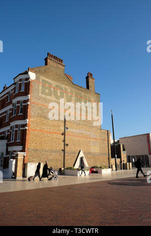 Vista verticale della gente camminare pedoni in Windrush Square e il Bovril edificio con cielo blu in Brixton a sud di Londra Inghilterra REGNO UNITO KATHY DEWITT Foto Stock