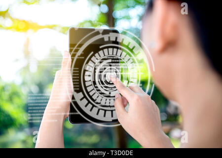 Vista posteriore del business donna toccare un cerchio nella schermata virtuale sulla tavoletta digitale quale visualizzare l'interfaccia di mappa del mondo e il codice binario del par Foto Stock