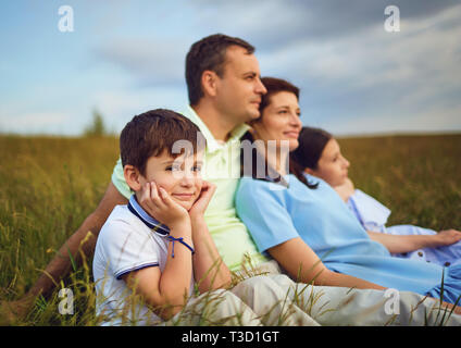 Famiglia insieme di riposo seduto su erba in natura. Foto Stock