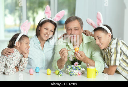 La famiglia felice di quattro indossando orecchie di coniglietto e pittura delle uova di Pasqua Foto Stock