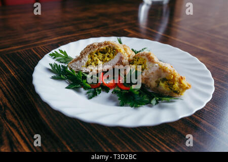 Pollo Kiev su crostini con purea di patate, sul tavolo di legno, su sfondo lucido Foto Stock