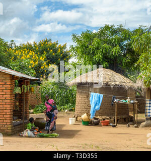 Le donne che trasportano i neonati salutarci nel villaggio del Malawi Foto Stock