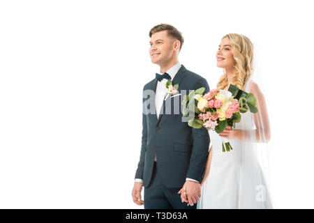 Sposa felice con un bellissimo mazzo di nozze tenendo le mani con sorridente groom isolato su bianco Foto Stock