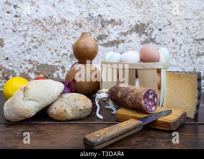 Tradizionale cibo spagnolo su un vecchio tavolo di legno, carne di maiale iberico salsicce, pane, uova, formaggio e verdure e un vecchio coltello Foto Stock