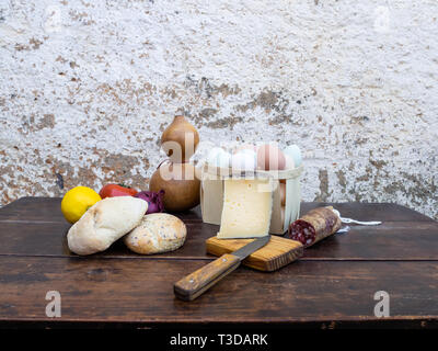 Tradizionale cibo spagnolo su un vecchio tavolo di legno, carne di maiale iberico salsicce, pane, uova, formaggio e verdure e un vecchio coltello Foto Stock