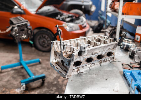 Messa a fuoco selettiva. Blocco del motore sul cavalletto di riparazione con il pistone e la biella di tecnologia automobilistica. Auto sfocata sullo sfondo. Interno di un automobile Foto Stock