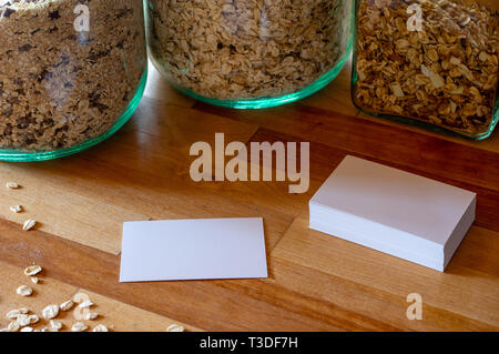 Business card mockup modelli su un tavolo con cosparso di farina di avena - muesli vasi in background Foto Stock