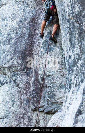 Un maschio di rocciatore esecuzione it out (salendo una lunga strada senza proteggere la caduta di potenziale) in poco fumo Bluffs area di arrampicata, Squamish, BC, Foto Stock