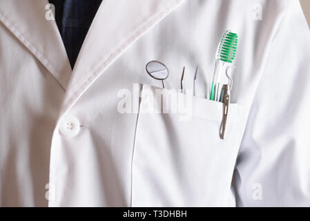 Manto bianco di dentista con strumenti in tasca. Composizione orizzontale. Vista frontale. Foto Stock