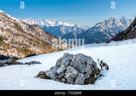 Vista dal campo nevoso con una roccia sul pass road Vrsic a. montagne Veliko Spicje, Trentski Pelc Srebrnjak e nel Parco Nazionale del Triglav nelle Alpi Giulie Foto Stock