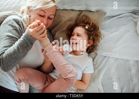 Un ritratto della bambina con la nonna avente il divertimento a casa. Foto Stock