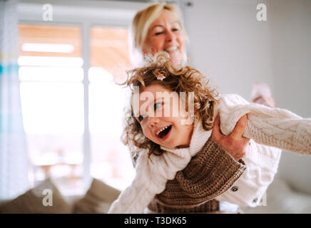 Un ritratto della bambina con la nonna avente il divertimento a casa. Foto Stock