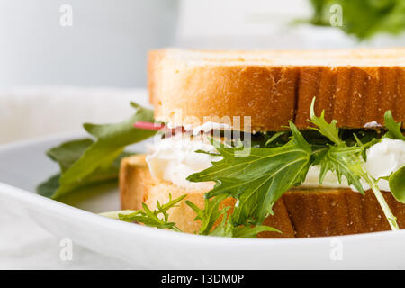 Una sana toast con formaggio di capra, avocado, rucola e pomodori secchi su tavola in legno rustico Foto Stock