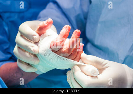 Chirurgo del bendaggio della mano di un paziente alla fine della chirurgia Foto Stock