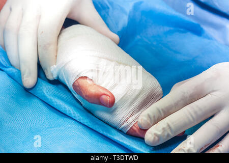 Chirurgo del bendaggio della mano di un paziente alla fine della chirurgia Foto Stock