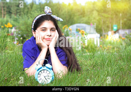 Ragazza sorridente con la sveglia nel giardino estivo Foto Stock