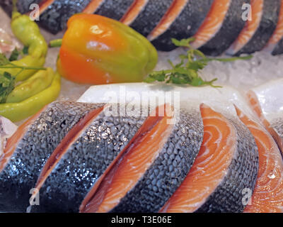 Salmone crudo su ghiaccio in un mercato del pesce con verdure Foto Stock