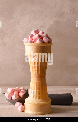Impilati coni gelato riempito con il colore rosa marshmallows e uno scoop in background. Foto Stock